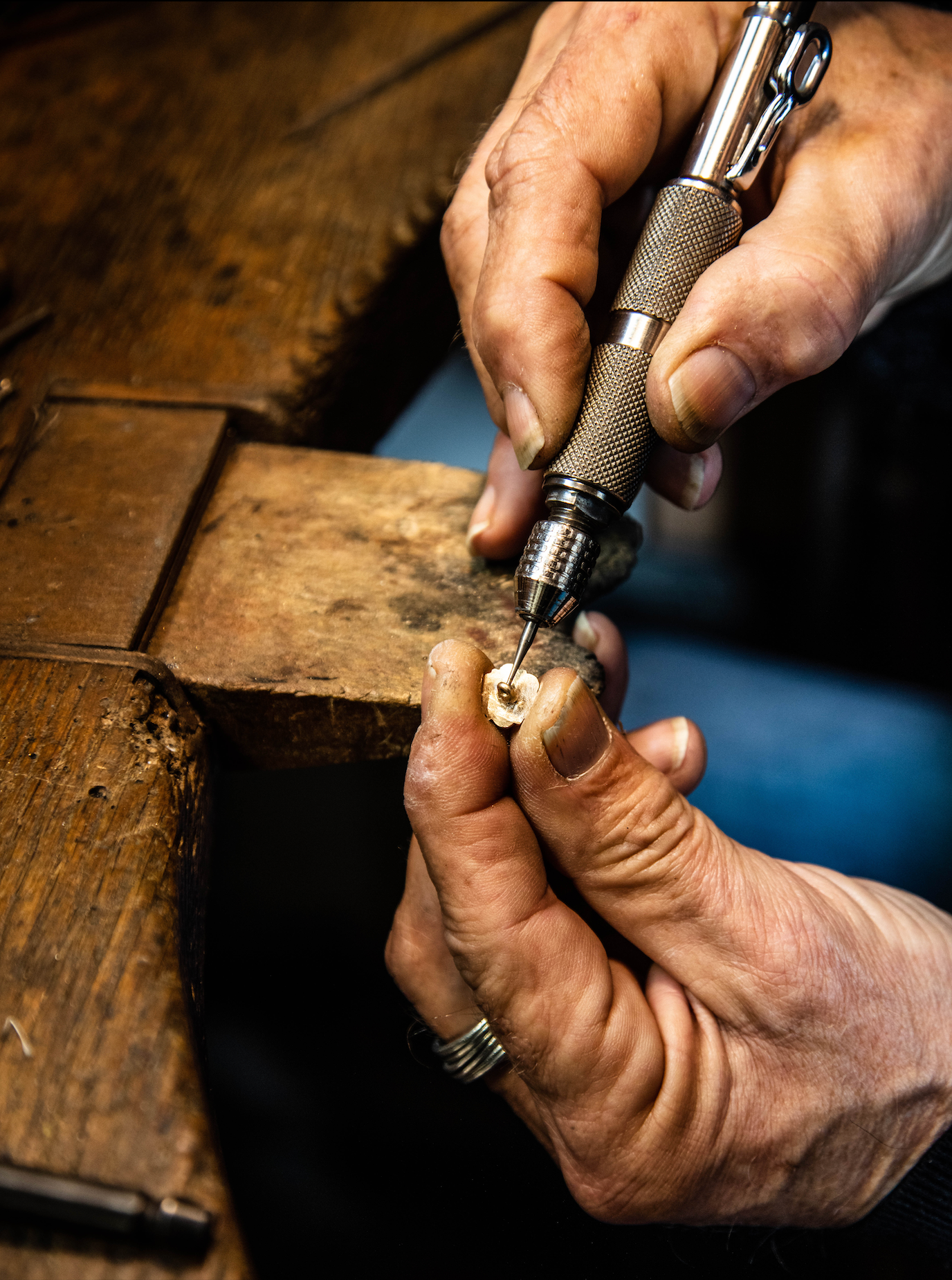 Mains d'artisan en train de façonner l'attache d'un bouton de manchette en plaqué or.