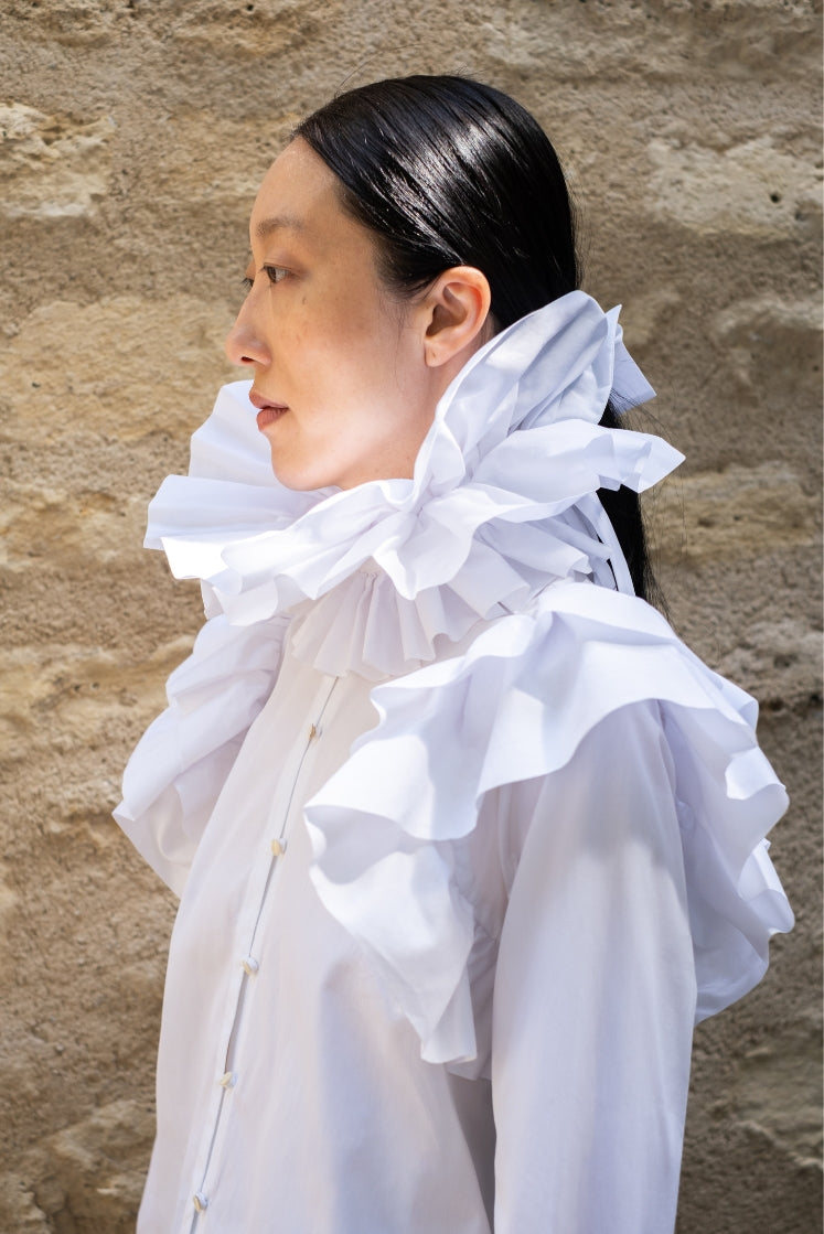 Femme portant la chemise FORTUNÉE issue de la collaboration entre Bourrienne Paris X et Charles de Vilmorin, vue de 3/4 mettant en valeur le grand volant au col et à l'emmanchure. 