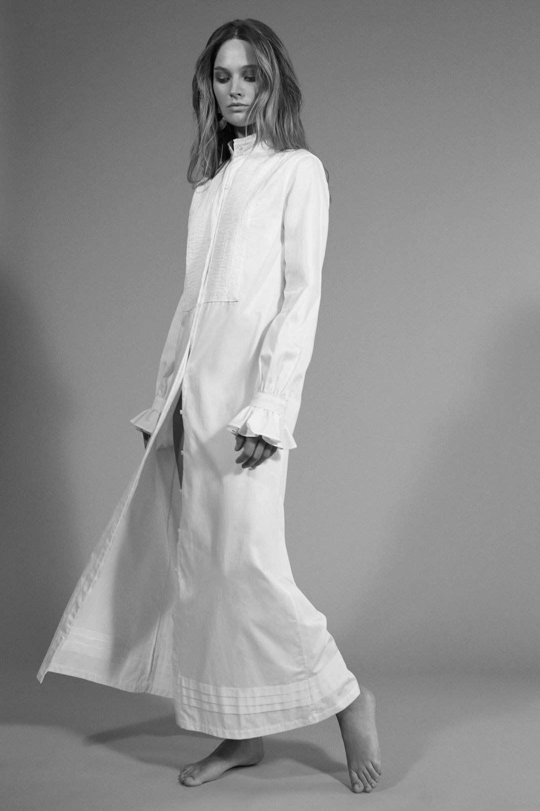 Femme portant une robe chemise blanche longue avec des poignets à volants.