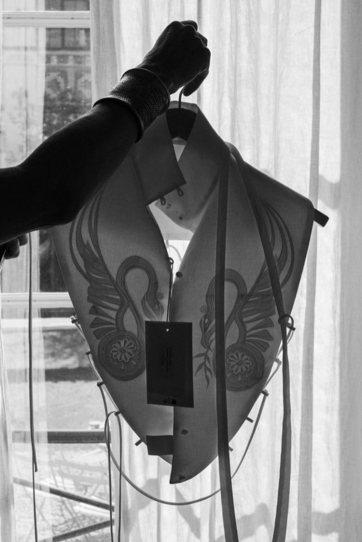 Plastron THERESA sur cintre, photo en noir et blanc où l'on distingue clairement les broderies à l'avant de la pièce.