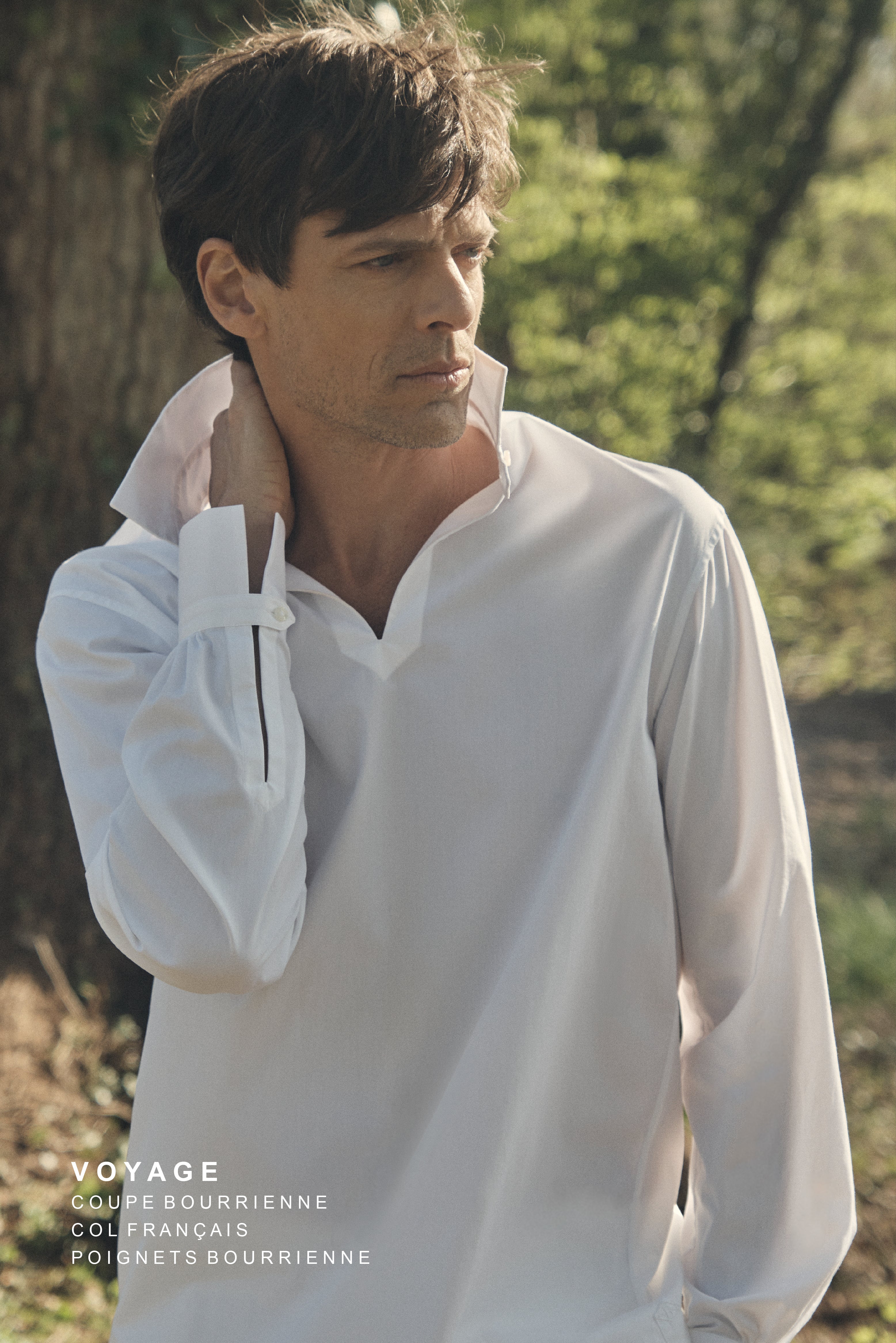Photo plan taille d'un homme portant une chemise qui se nomme VOYAGE, elle est en 100% Coton, fabriqué en Europe, une coupe Bourrienne, un col Français et des poignets Bourrienne. Sa main droite tient sa nuque, on voit bien les détails des poignets  
