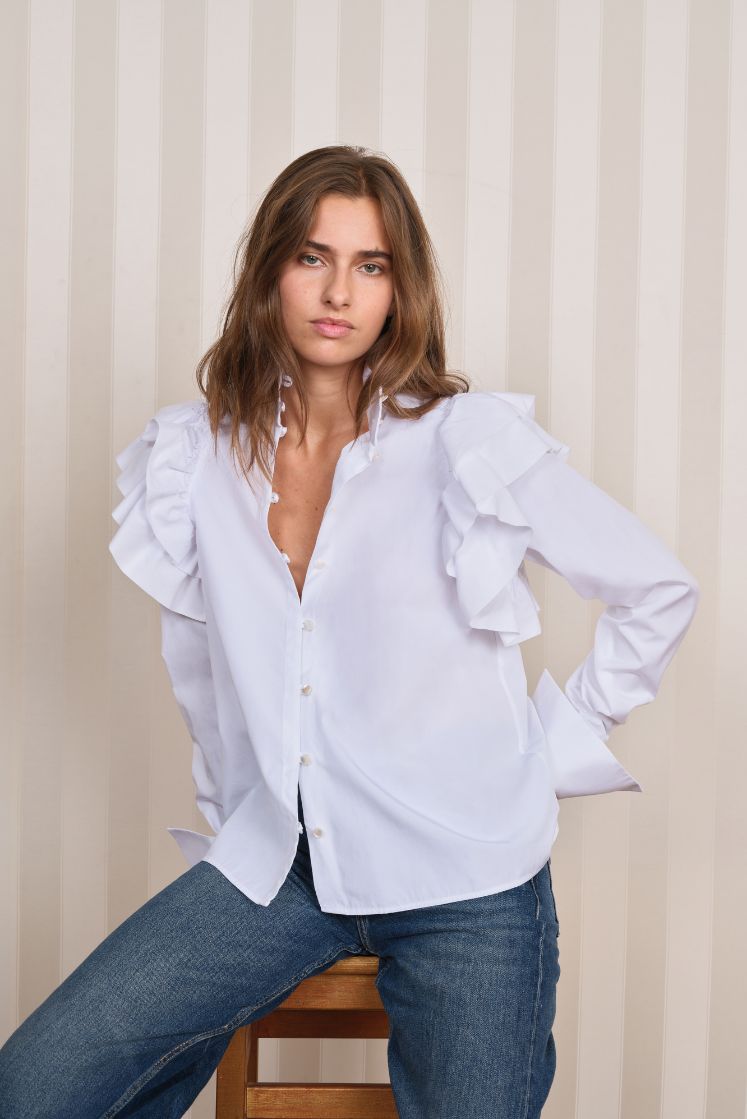 Femme portant la chemise FORTUNÉE avec des volants sur les épaules. 