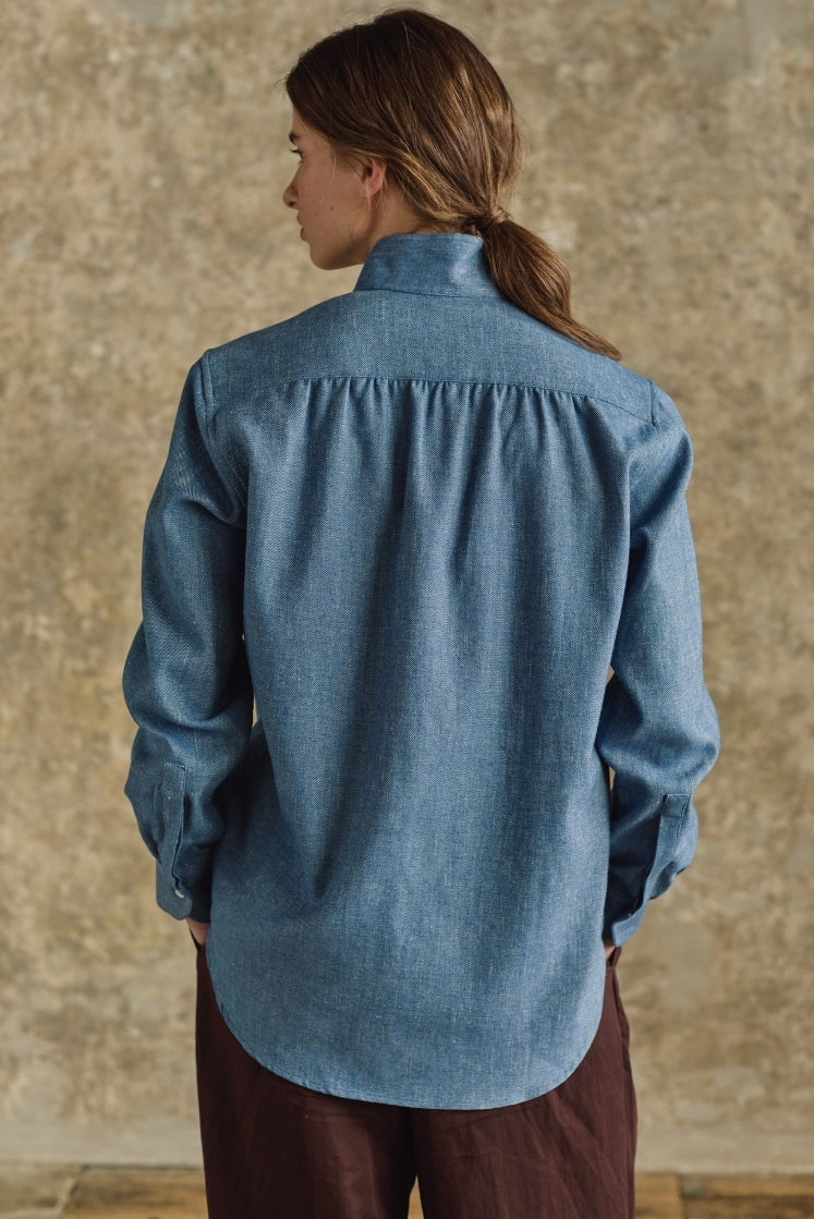 femme de dos portant la chemise amazone en denim bleu clair, vue  sur les fronces au dos de la chemise 
