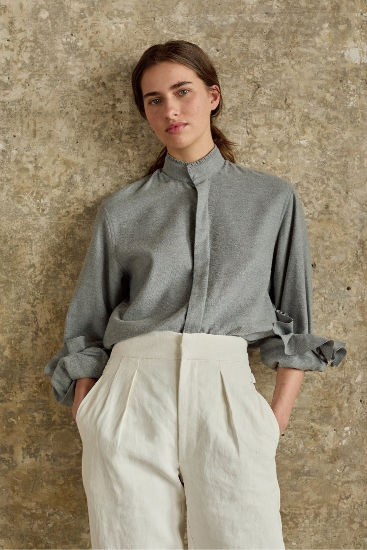 Chemise en flanelle grise pour femme avec col ancien à petits volants, manches retroussées avec poignets à volants, associée au pantalon blanc HORIZON en lin plâtré