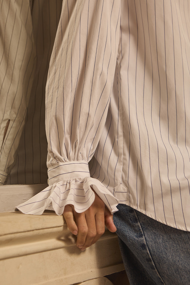 Closeup sur le poignet à volants de la chemise BOUDOIR à rayures bleu marine.