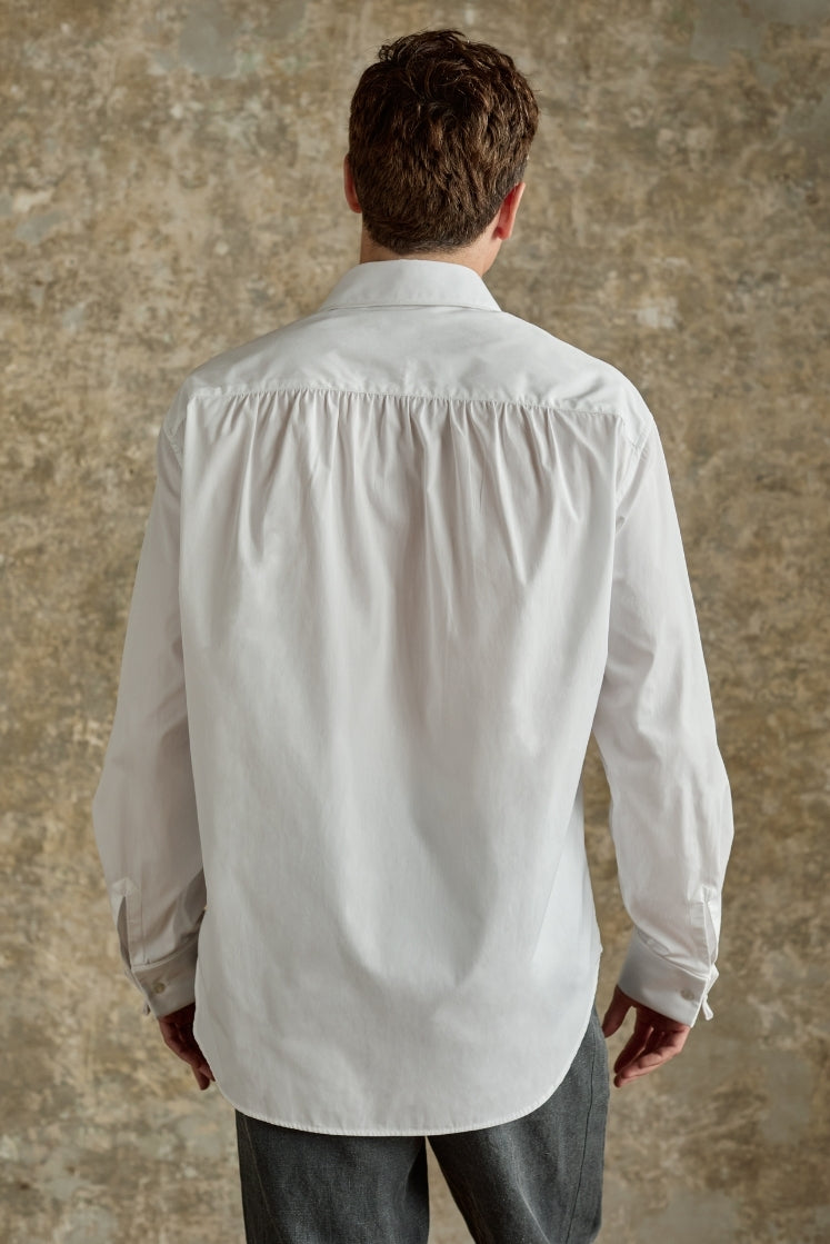 Homme portant la chemise blanche GALERIE en popeline de coton avec de délicates fronces dans le dos, coupe Bourrienne. 