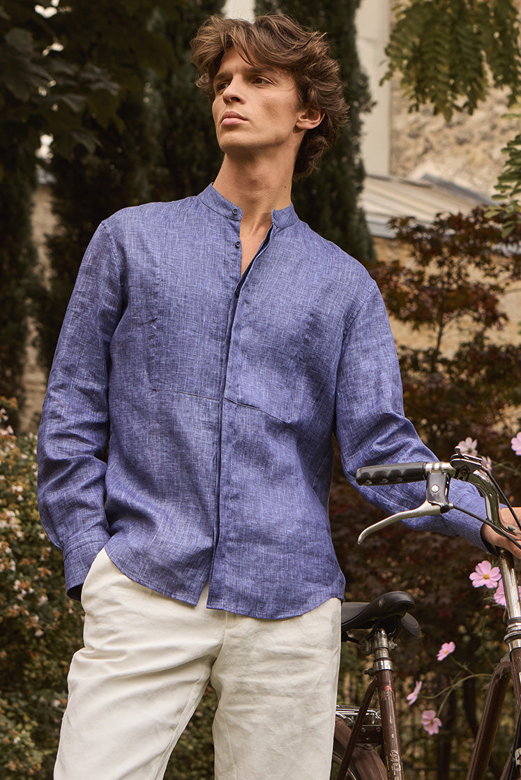 Homme dans un jardin portant une chemise en lin bleu au col officier avec plastron ton sur ton.