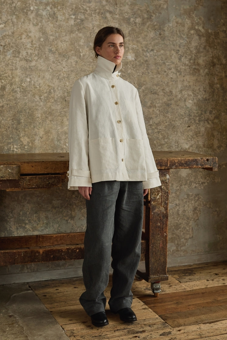 Femme portant une veste en lin plâtré blanche Bourrienne Paris X inspirée des vestes militaires, avec le pantalon Bourrienne en lin plâtré gris anthracite. 