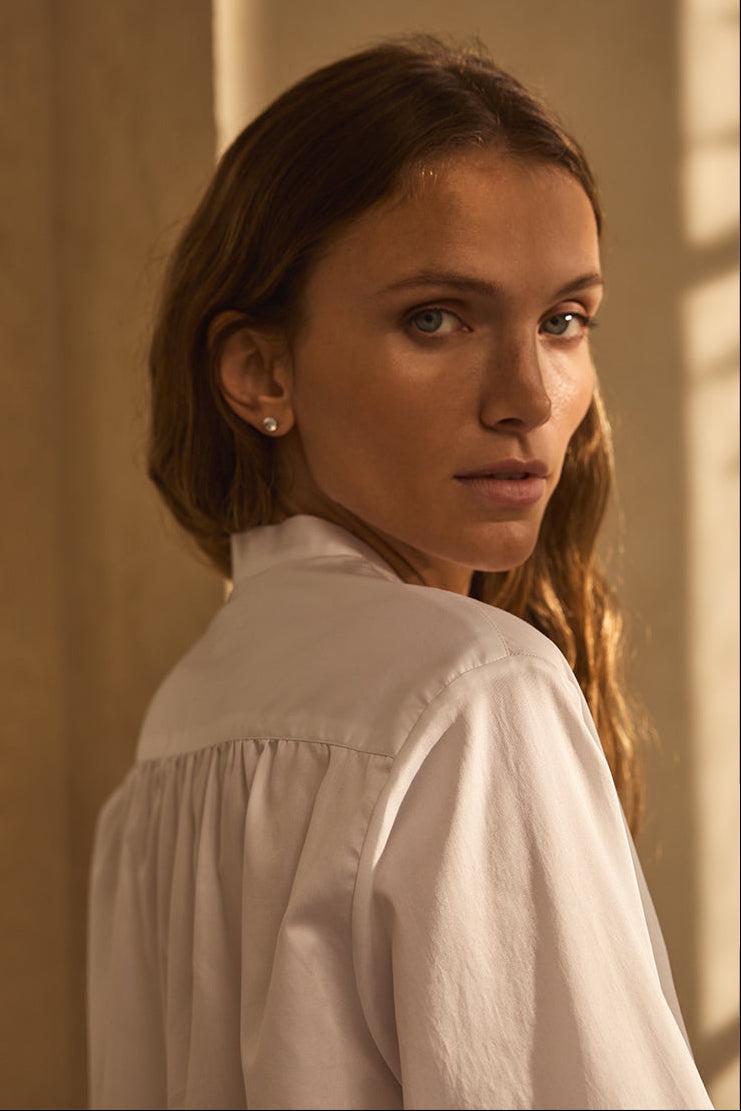 Plan épaule de d'une femme de trois-quarts dos portant une chemise planche avec des fronces dans le dos.