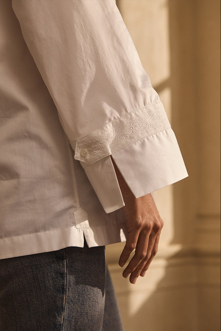 Closeup sur le poignet d'une chemise blanche avec un galon brodé.