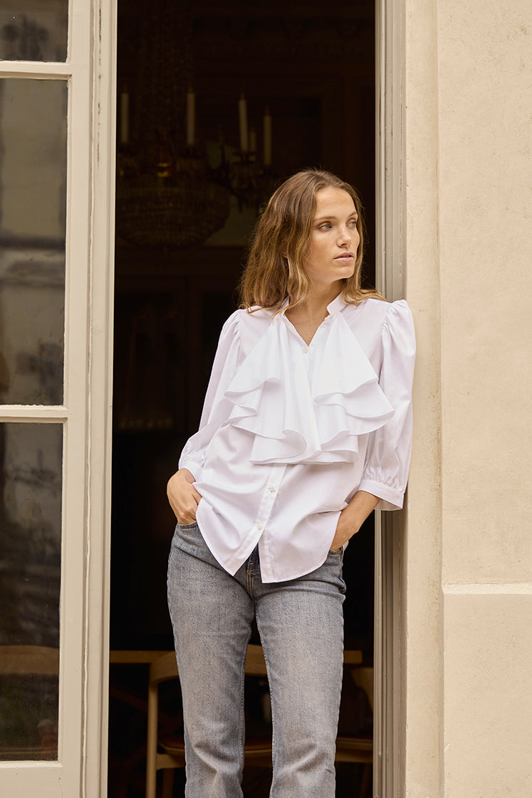 Femme portant la chemise blanche REVERIE, avec un jabot et des manches bouffantes coupées 3/4.