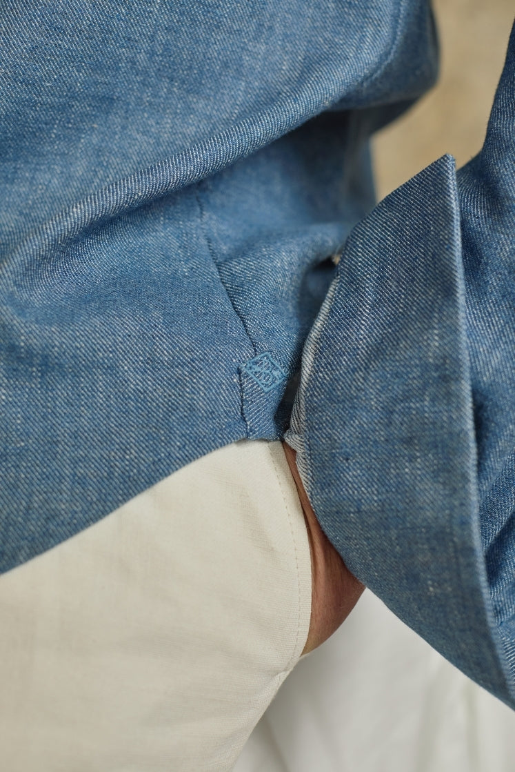 Zoom sur l'hirondelle brodée du logo Bourrienne sur le côté de la chemise SCULPTEUR en denim bleu clair. 