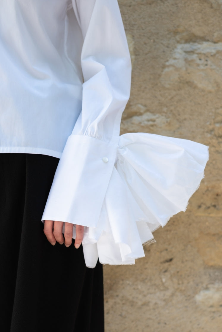 Closeup sur le poignet allongé de la chemise Juliette, avec la fleur attachée au poignet. 