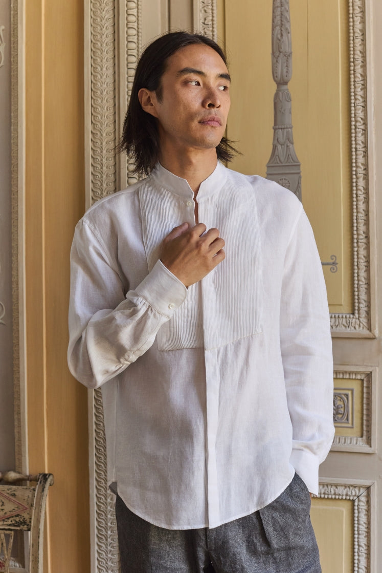 Homme portant une chemise blanche en lin avec un plastron plissé.