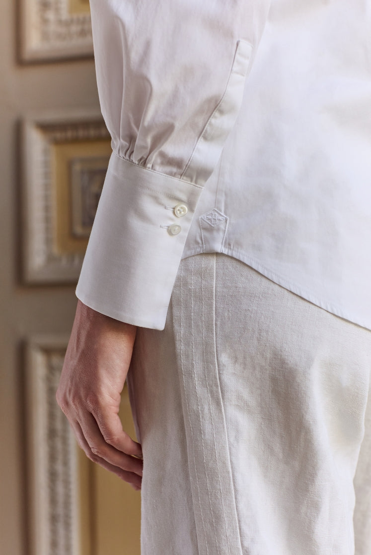 Close-up sur le poignet allongé de la chemise blanche CROISIÈRE. 