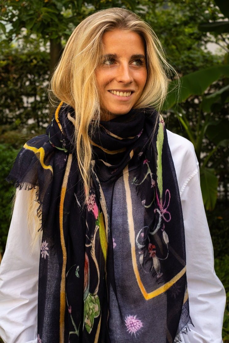 Femme portant l'écharpe Fortunée en cachemire navy aux motifs de l'Hôtel de Bourrienne. 