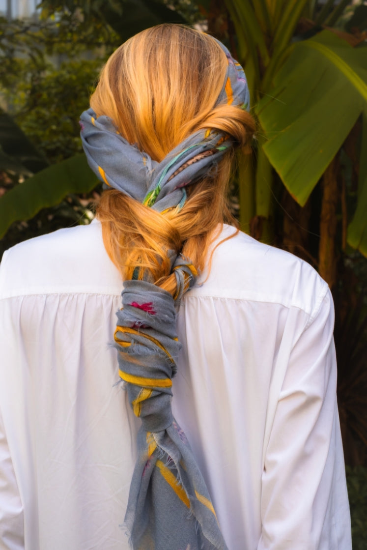 Femme portant l'écharpe Fortunée en cachemire bleu ciel attachée en tresse dans ses cheveux.
