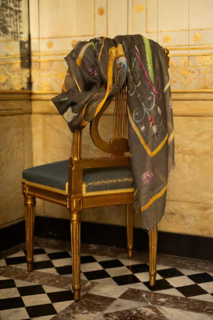 Écharpe Fortunée en cachemire grise à motifs posée sur une chaise dans l'Hôtel de Bourrienne. 