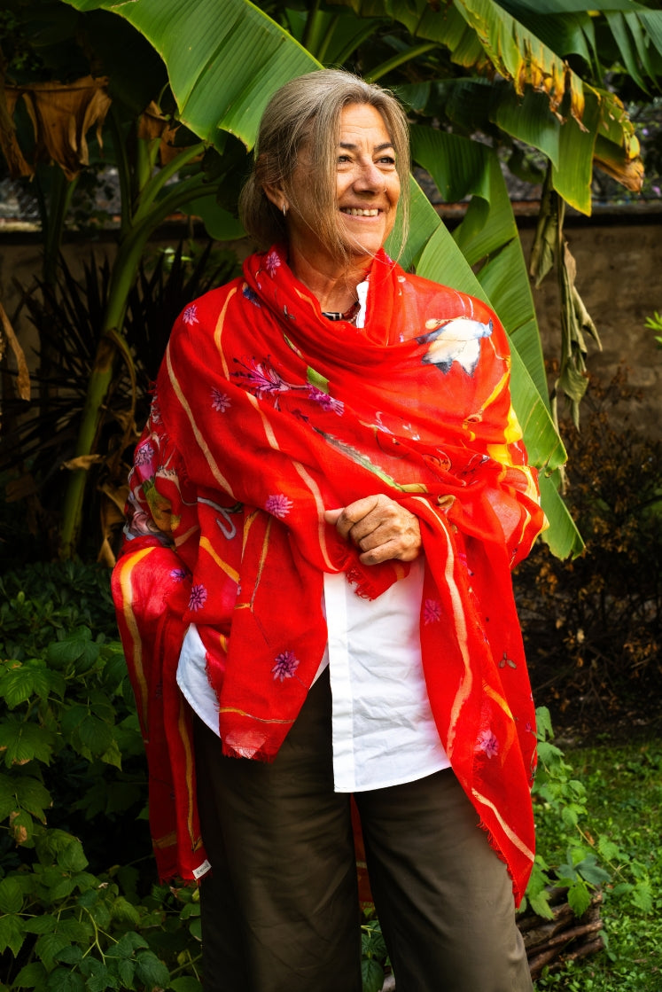 Femme portant l'écharpe Fortunée en cachemire rouge dans un jardin. 