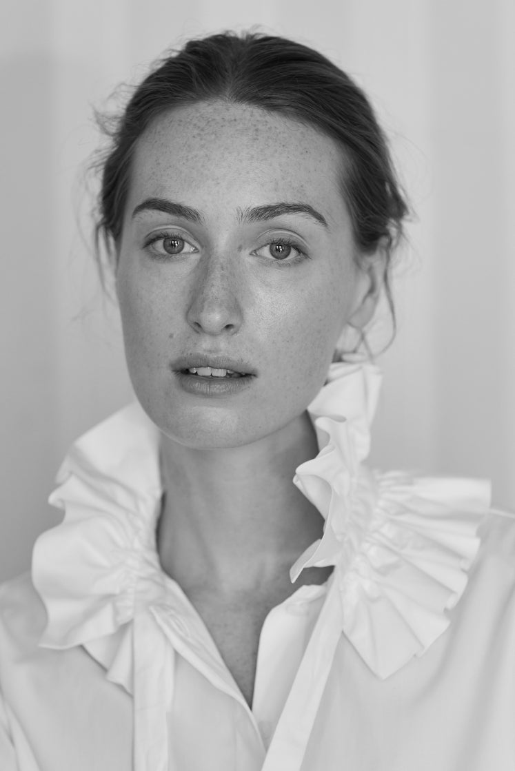 Femme portant la chemise PASTEL blanche avec son grand col à volants inspiré des cols fraise d'époque, plan buste. 