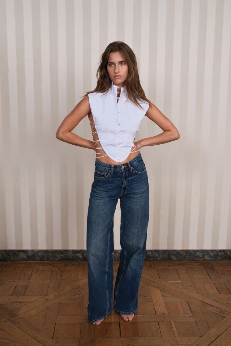 Femme portant le plastron THÉRÉSA à dos nu avec laçage associé à un jean. 