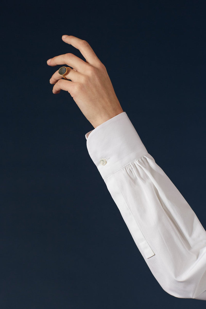 La chemise AMAZONE en blanc immaculé, pièce centrale de la collection Bourrienne, revisite élégamment le col ancien et présente des fronces distinctives à l'arrière, ajoutant une touche de raffinement.