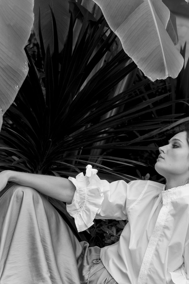 BOUDOIR, l'essence du chic à la française. Coupée dans une popeline fraîche, sa silhouette ample séduit. Col officier orné d'un galon inspiré des fresques de l'Hôtel de Bourrienne, manches légèrement bouffantes agrémentées de volants et de galons brodés, font de cette chemise une pièce originale et sophistiquée.